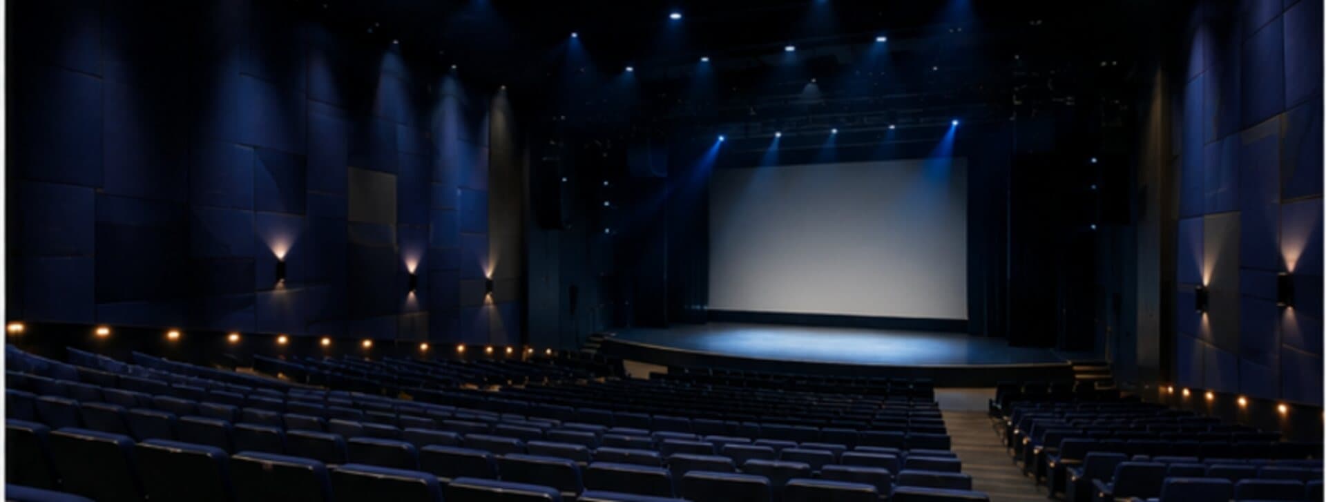 Salle de spectacle vue depuis les gradins, écran et scène éclairés