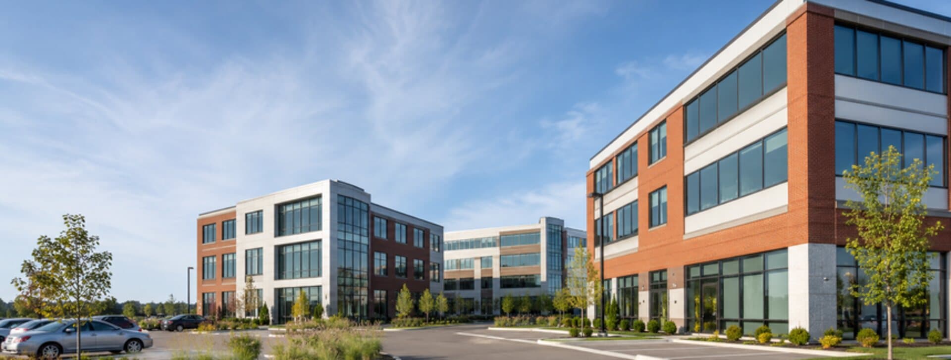 Immeuble de bureaux de trois étages vu de l'extérieur, stationnement au premier plan