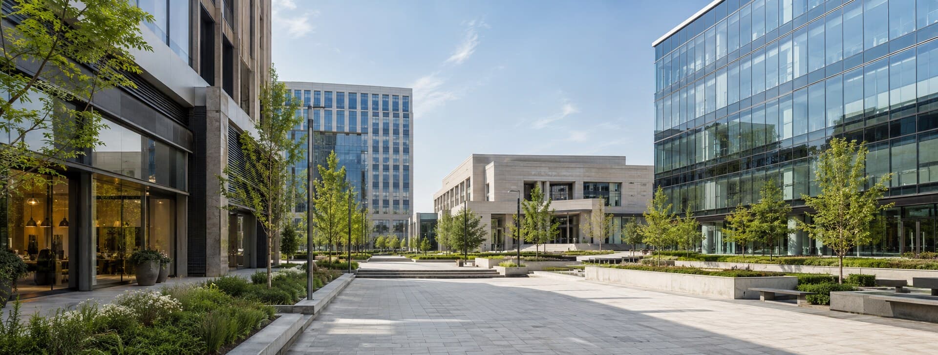 Ensemble d'immeubles de bureaux vitrés bordant une allée piétonne paysagée